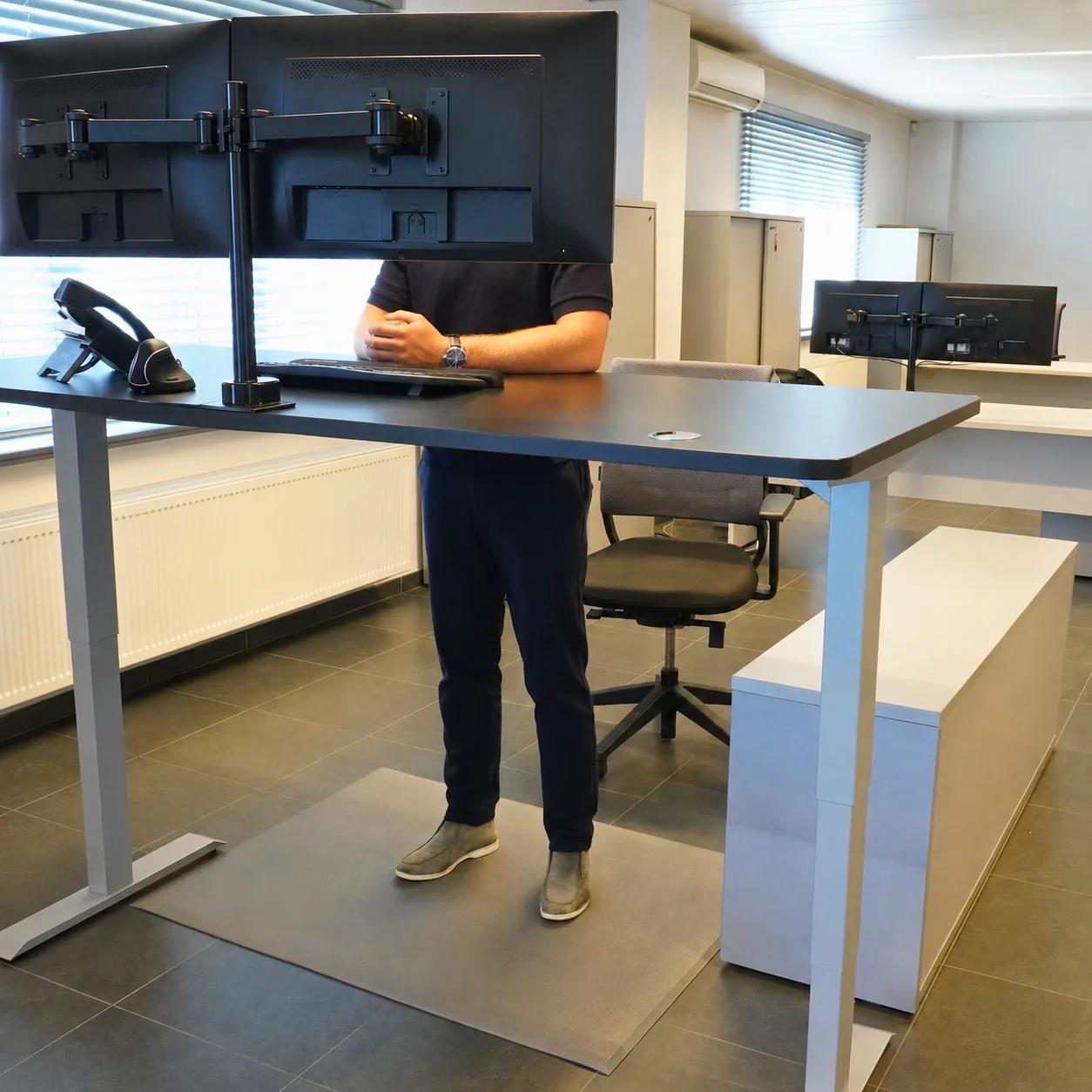 M1 grey anti-fatigue mat under a sit-stand desk in an office