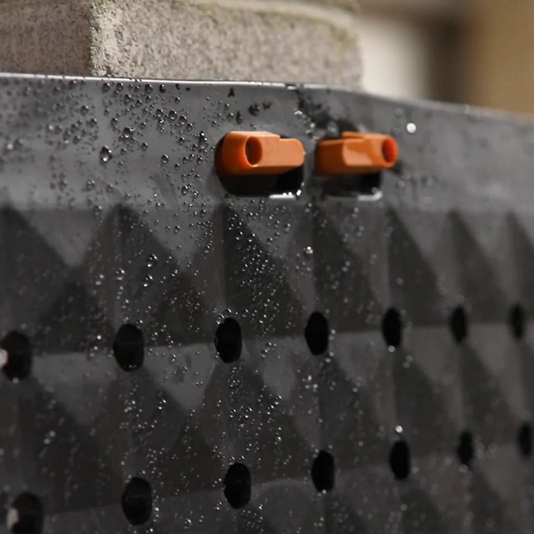 M-Lite vertical hangers installed holding a drainage mat against a wall — application example shown in orange; the hanger sold here is black